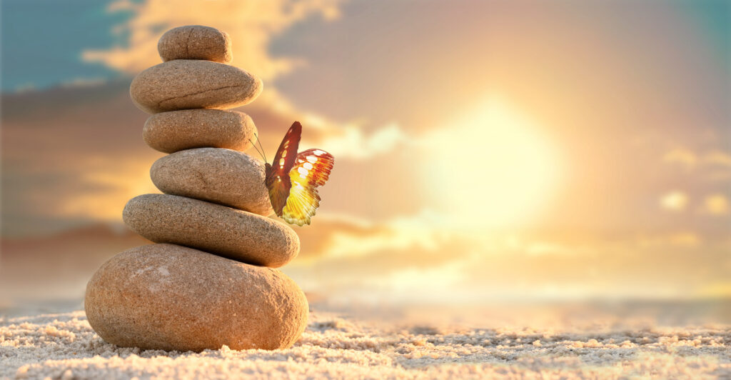 Steinturm im Sonnenuntergang am Meer. Schmetterling sitzt an dem Stein. Der Ausweg aus Krankheit, wie beispielsweise einer Depression.